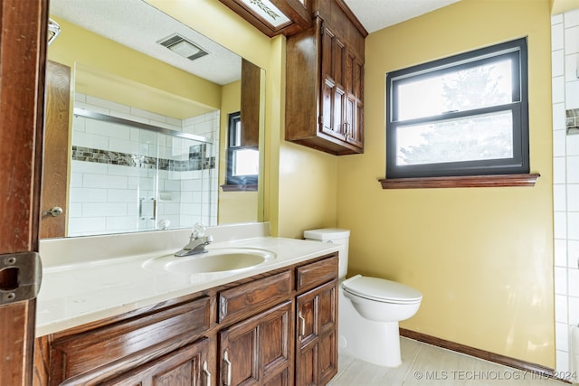 bathroom featuring a shower with door, a textured ceiling, toilet, vanity, and tile patterned floors