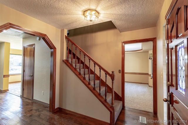 foyer entrance featuring a textured ceiling and dark hardwood / wood-style floors