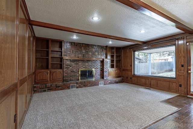 unfurnished living room with a textured ceiling, wooden walls, a fireplace, and dark hardwood / wood-style floors