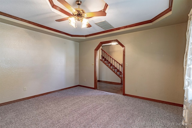 carpeted empty room featuring ceiling fan, a raised ceiling, and ornamental molding