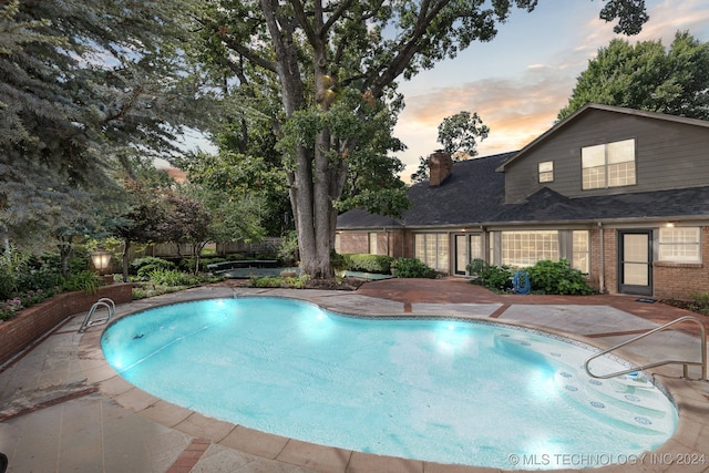 pool at dusk featuring a patio area