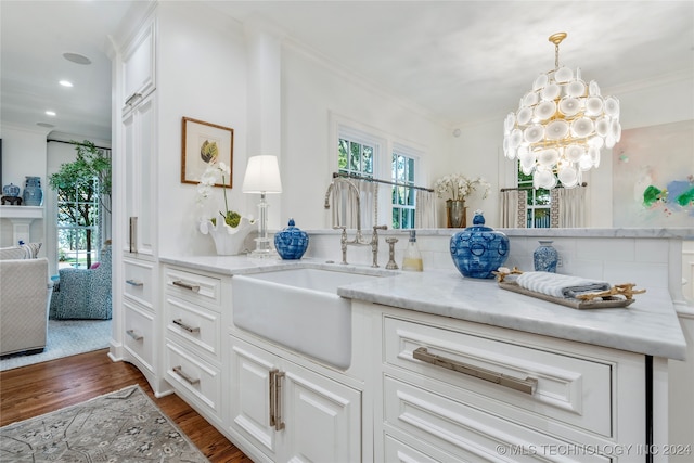 kitchen featuring hanging light fixtures, light stone counters, ornamental molding, dark hardwood / wood-style floors, and sink