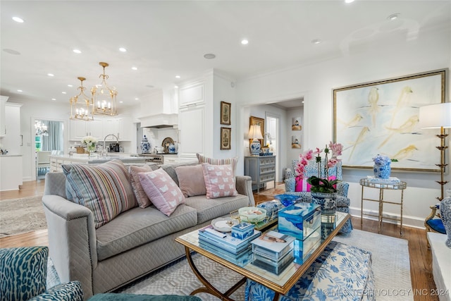 living room featuring crown molding, hardwood / wood-style flooring, and a chandelier