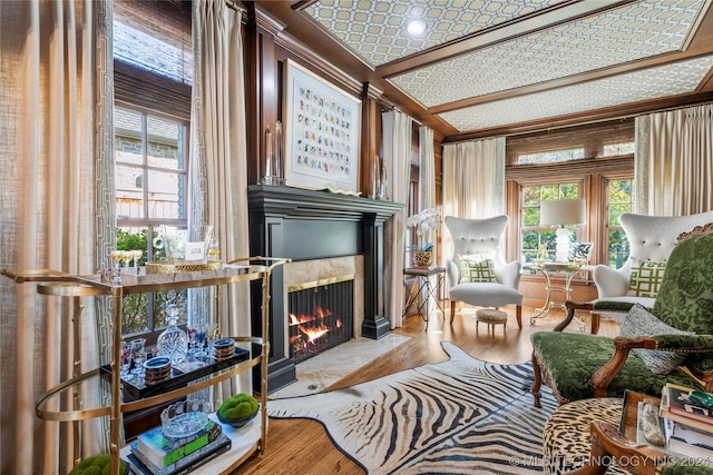 living area featuring a premium fireplace, crown molding, and hardwood / wood-style flooring