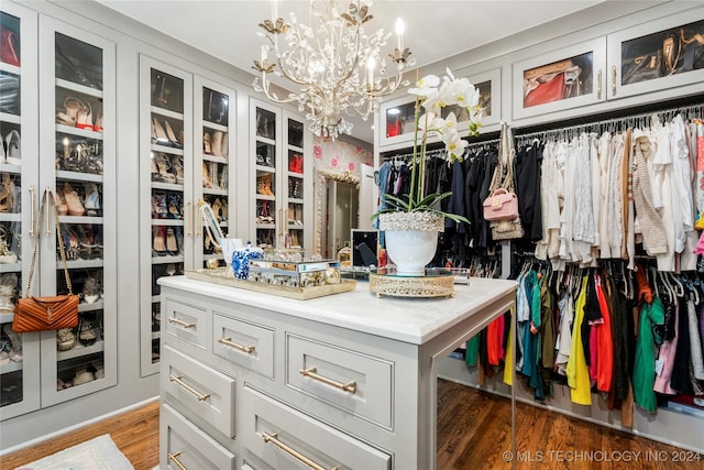 walk in closet featuring a notable chandelier and dark hardwood / wood-style flooring