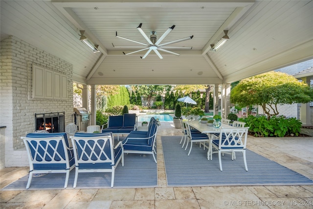 view of patio with an outdoor brick fireplace and ceiling fan