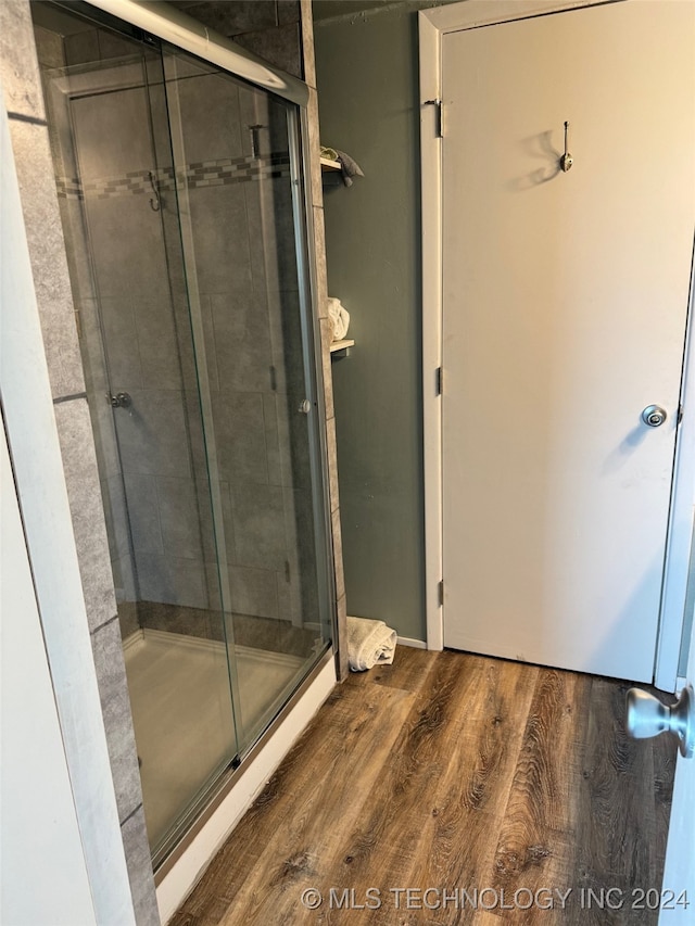 bathroom with wood-type flooring and a shower with shower door