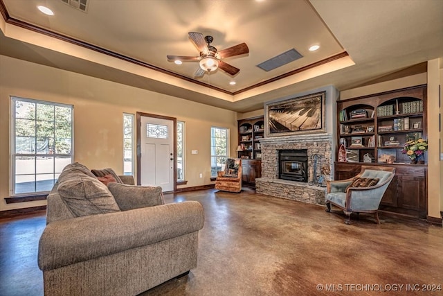 living room with a tray ceiling, a fireplace, and ceiling fan