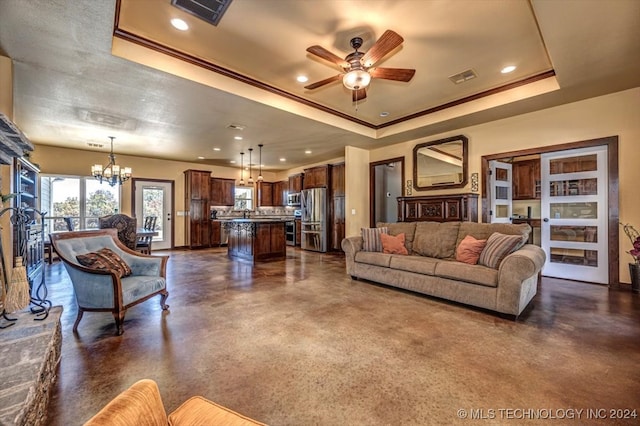 living room featuring a raised ceiling and ceiling fan with notable chandelier