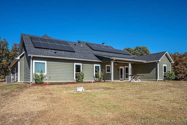 back of property with a patio, a lawn, and solar panels