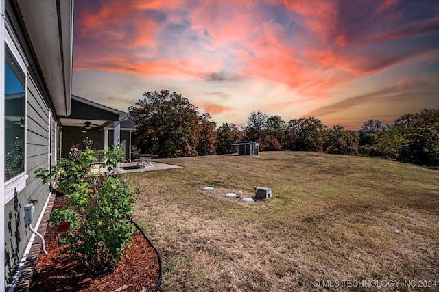 yard at dusk featuring a patio and ceiling fan