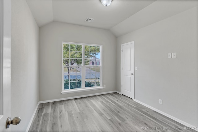 spare room featuring light hardwood / wood-style flooring, lofted ceiling, and a healthy amount of sunlight