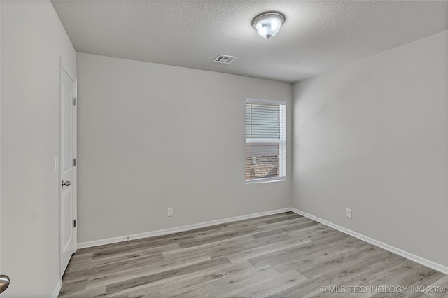 spare room featuring light hardwood / wood-style flooring and a textured ceiling