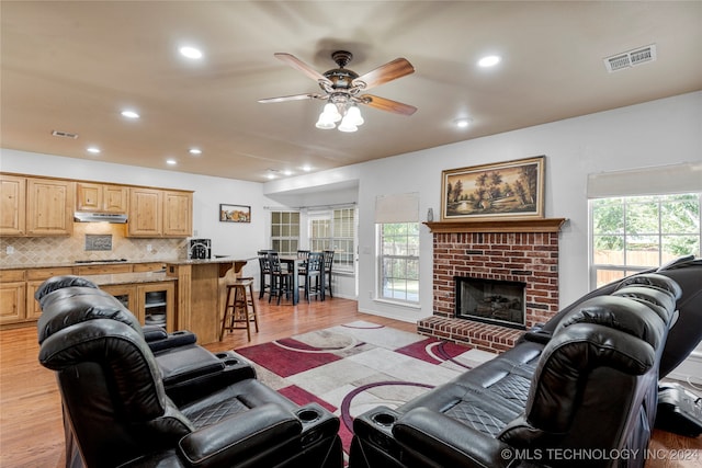 living room with ceiling fan, light hardwood / wood-style flooring, and a fireplace