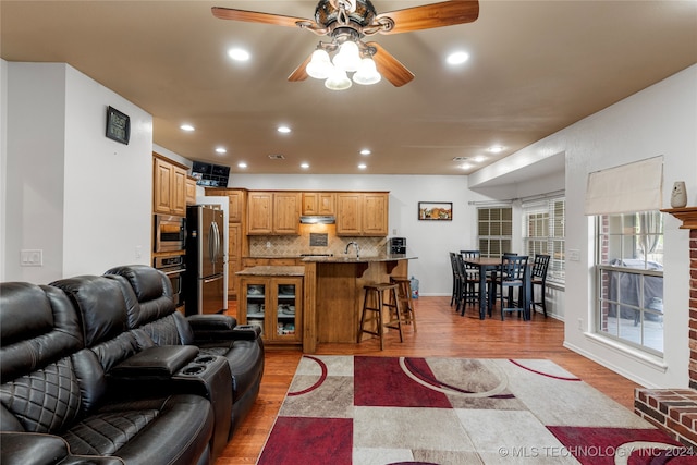 living room featuring sink, light wood-type flooring, and ceiling fan