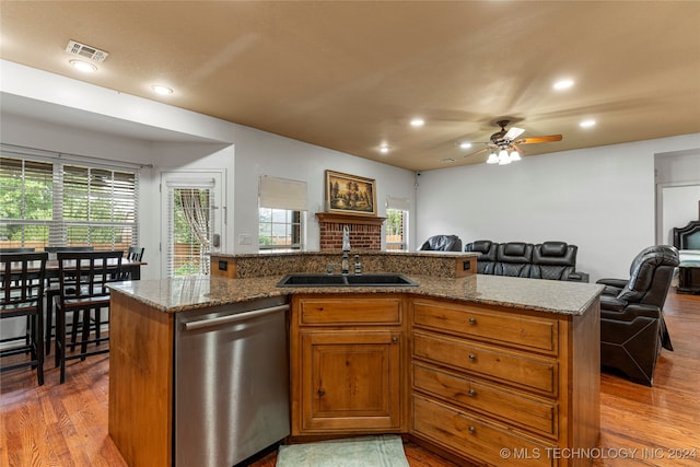 kitchen with ceiling fan, light stone countertops, stainless steel dishwasher, light hardwood / wood-style flooring, and sink