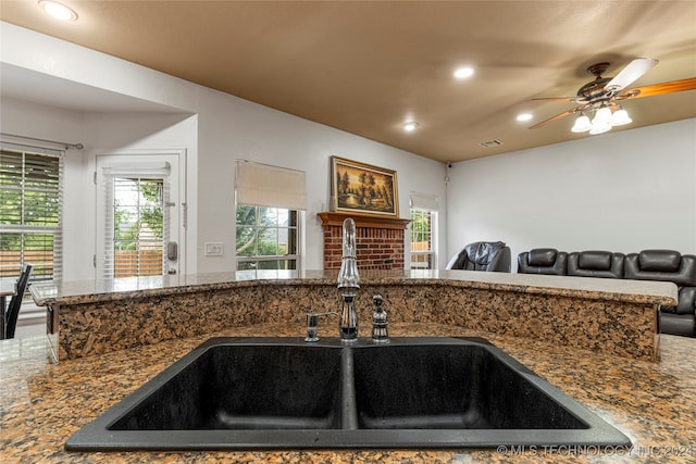 kitchen with sink, dark stone counters, and ceiling fan