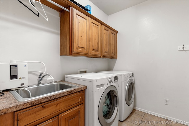 laundry room with sink, washer and dryer, light tile patterned flooring, and cabinets