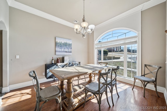 dining space featuring hardwood / wood-style floors, ornamental molding, and a chandelier