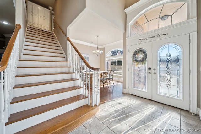 tiled entrance foyer featuring an inviting chandelier, ornamental molding, and french doors