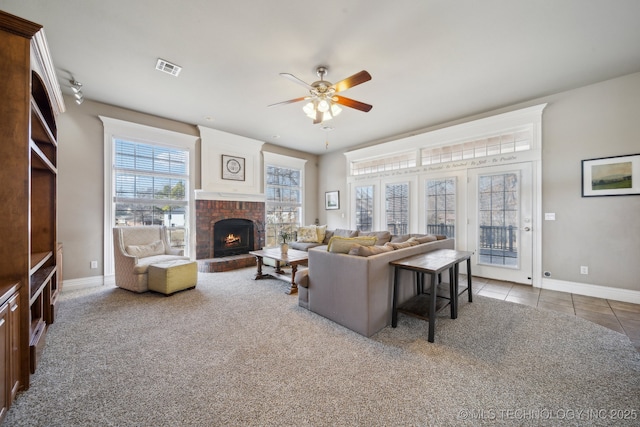 tiled living room featuring ceiling fan and a brick fireplace