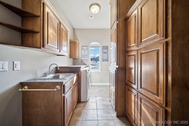 laundry area with cabinets, separate washer and dryer, sink, and light tile patterned floors