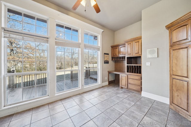 unfurnished office with light tile patterned floors, built in desk, and ceiling fan