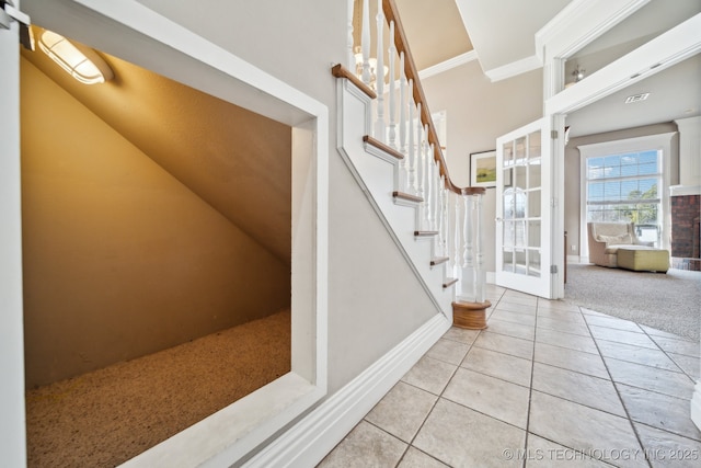 staircase with ornamental molding and tile patterned floors