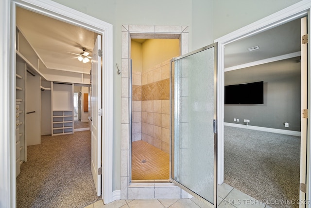 bathroom with ceiling fan, a shower with door, and tile patterned flooring