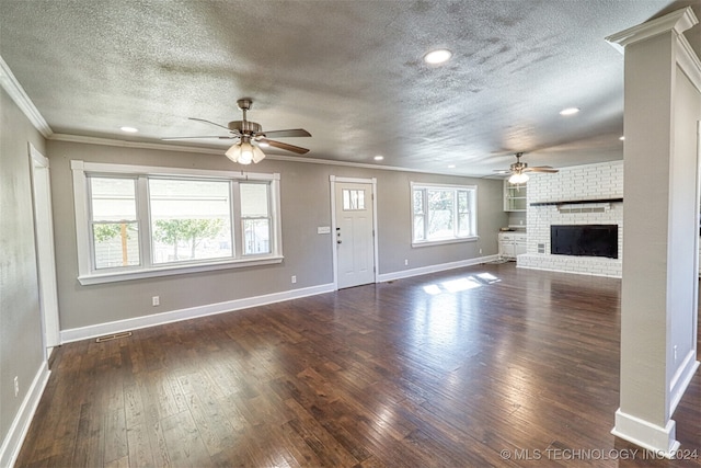 unfurnished living room with a fireplace, a textured ceiling, ceiling fan, ornamental molding, and dark hardwood / wood-style floors