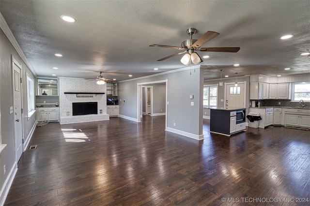 unfurnished living room with crown molding, a brick fireplace, a textured ceiling, and dark hardwood / wood-style flooring