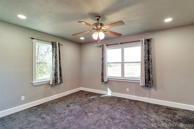 spare room with ceiling fan, a textured ceiling, and dark colored carpet