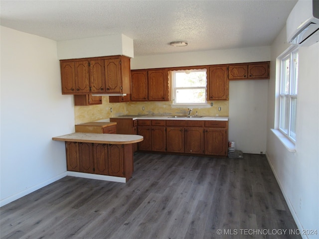 kitchen with a wall mounted AC, kitchen peninsula, tasteful backsplash, and dark hardwood / wood-style flooring