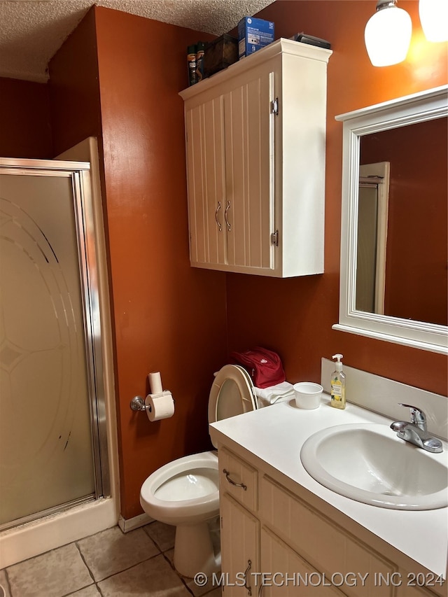 bathroom featuring a textured ceiling, toilet, vanity, an enclosed shower, and tile patterned floors