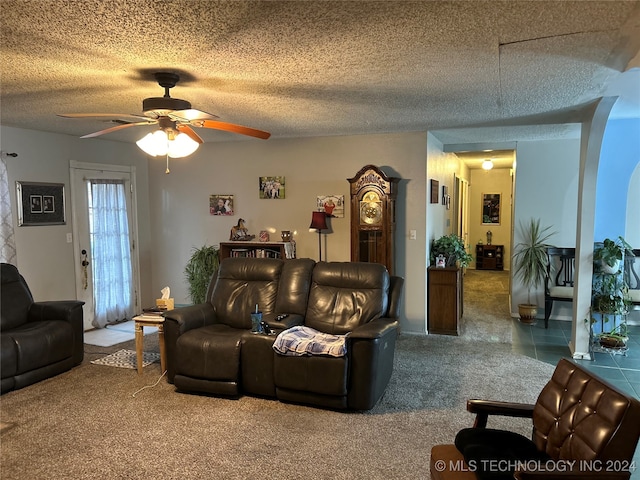 carpeted living room featuring ceiling fan and a textured ceiling