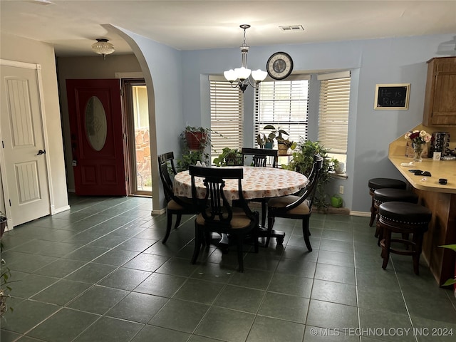 dining room with a chandelier and dark tile patterned floors