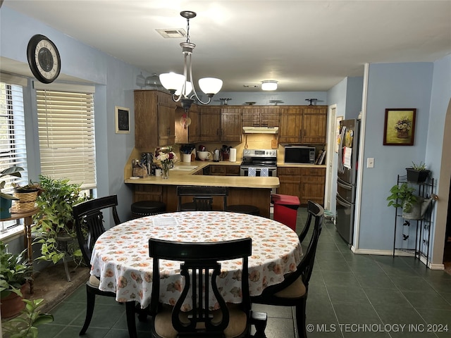 kitchen featuring dark tile patterned floors, kitchen peninsula, black appliances, a notable chandelier, and pendant lighting