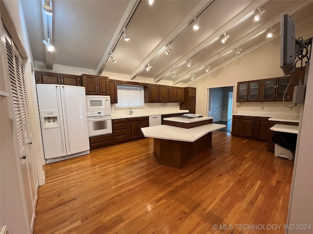 kitchen featuring white appliances, light hardwood / wood-style floors, a center island, and vaulted ceiling with beams