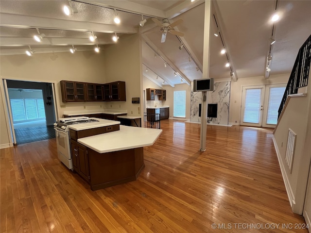 kitchen featuring white gas range oven, dark brown cabinets, a center island, ceiling fan, and light hardwood / wood-style flooring