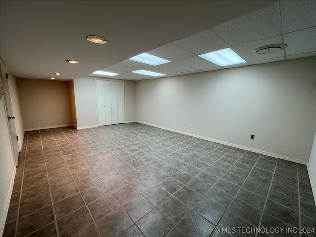 unfurnished room with a drop ceiling and dark tile patterned floors