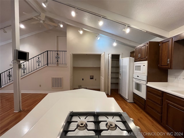 kitchen featuring dark hardwood / wood-style floors, lofted ceiling with beams, rail lighting, and white appliances