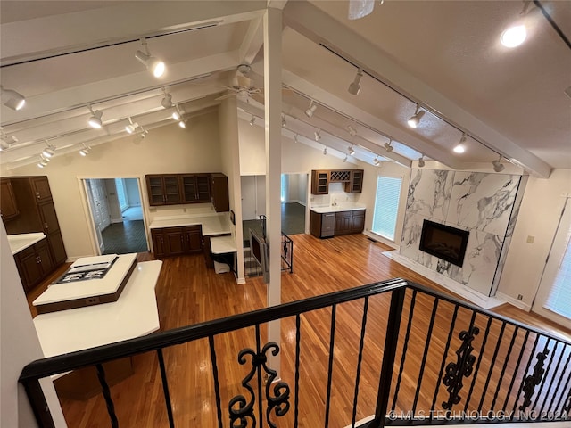 living room featuring a high end fireplace, lofted ceiling with beams, rail lighting, light wood-type flooring, and ceiling fan