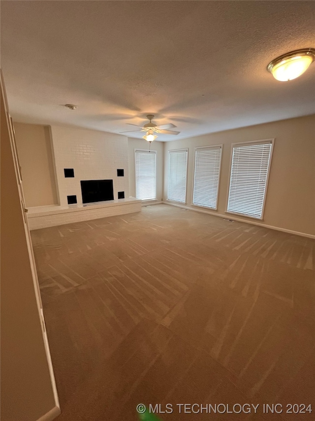 unfurnished living room with a textured ceiling, carpet floors, and ceiling fan