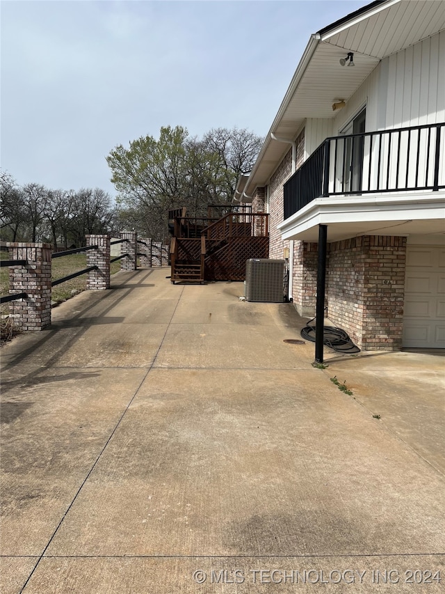 view of side of home with central AC, a balcony, and a garage