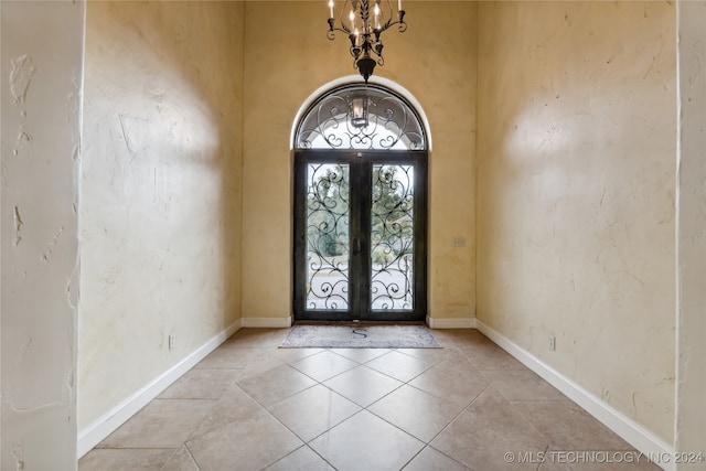 foyer featuring french doors, light tile patterned floors, and an inviting chandelier