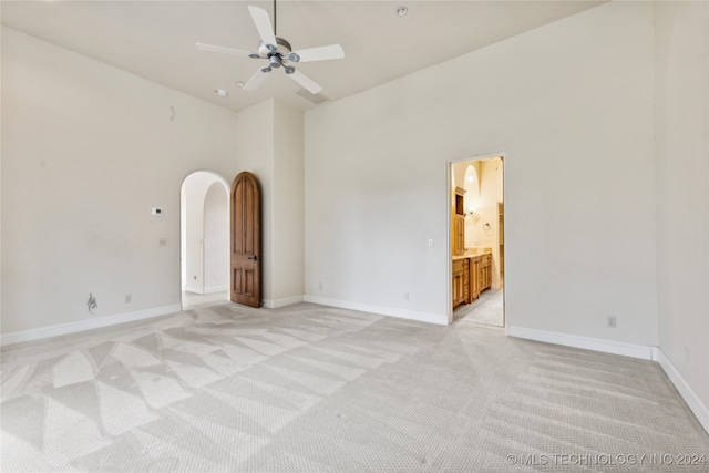 carpeted empty room with a high ceiling and ceiling fan