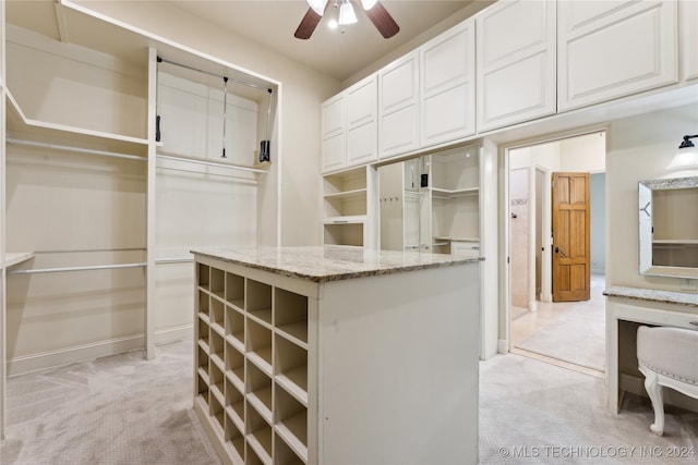 walk in closet with light carpet and ceiling fan