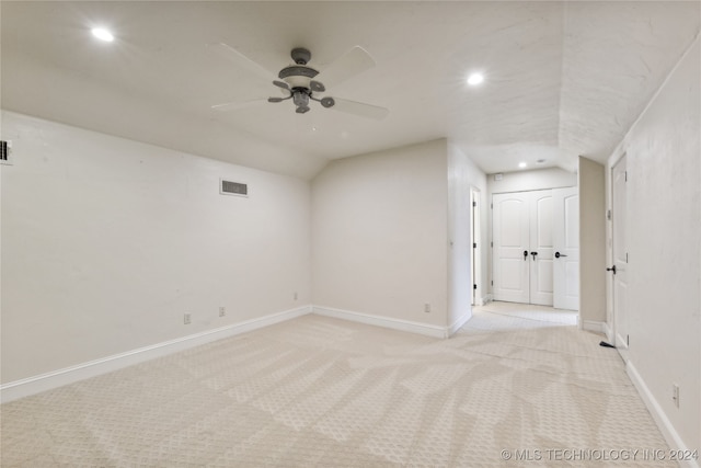 empty room featuring ceiling fan, vaulted ceiling, and light colored carpet