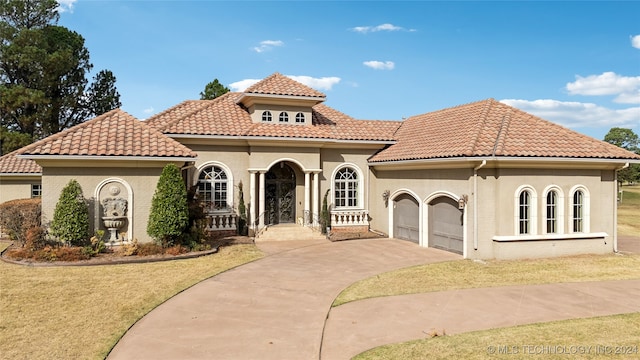 mediterranean / spanish-style home featuring a front lawn and a garage