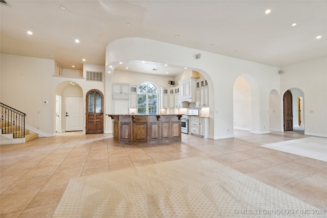 kitchen featuring light stone counters, a breakfast bar area, light tile patterned floors, stainless steel range, and a center island